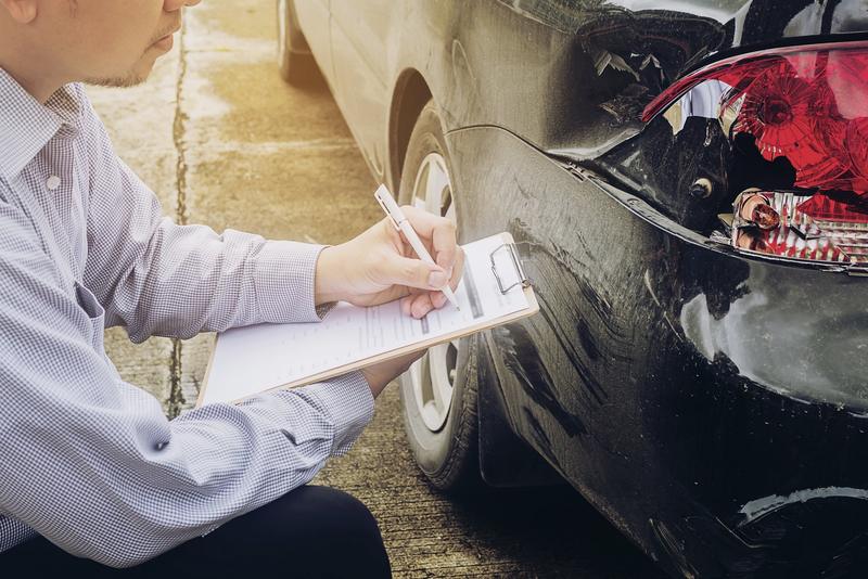Kfz-Sachverständiger dokumentiert einen Unfallschaden am Heck eines Autos